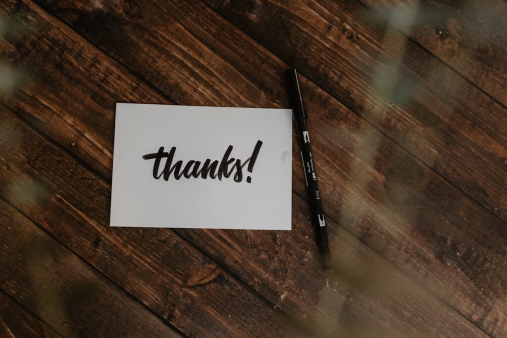 thank you message on paper and black pen on wood surface